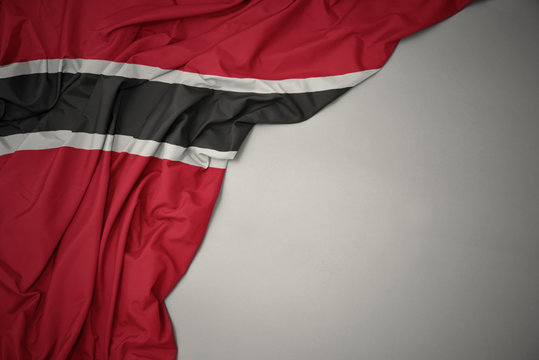 waving national flag of trinidad and tobago on a gray background.