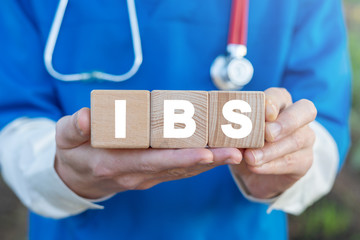 Physician holds three wooden blocks with IBS acronym. IBS Irritable Bowel Syndrome Health Care concept.