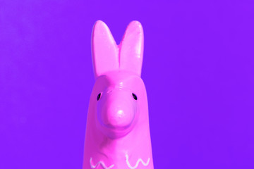 Pink zine type head of a toy lama on a glowing purple background close up. Creative and fun trendy collage animal concept with copy space