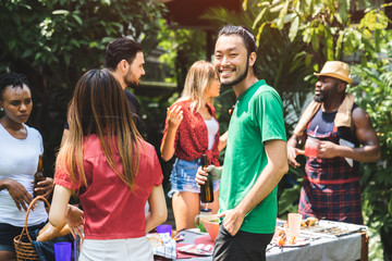 Young man and Group of friends making barbecue in the backyard. At summer outdoor party and holidays concept.