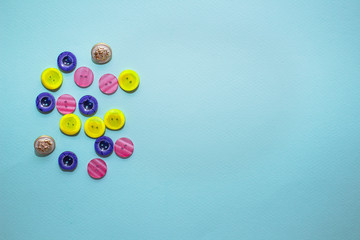 collection of various multicolored sewing button on blue background. Yellow, purple, dark blue buttons. Minimalism. Sewing accessories. Flatlay, place for text