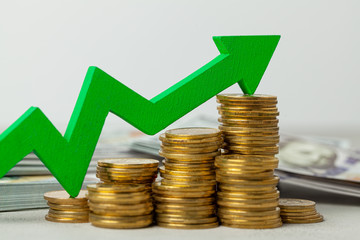 Green arrow up graphics on a stack of coins. The concept of profit growth and indicators.