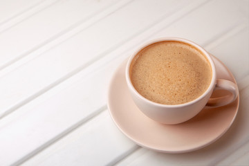 Cup of coffee with foam on white table