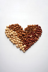 Heart shaped composition with almonds, hazelnuts and peanuts isolated on white background