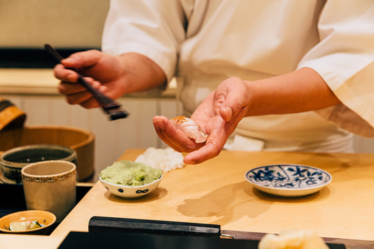 Japanese Omakase making Trout Sushi and adding Shoyu sauce on fish neatly by brush in his palm. Japanese traditional and luxury meal.