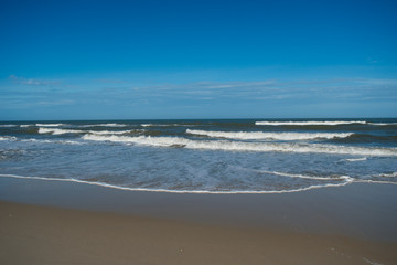 Waves gently rolling in on the Atlantic Ocean under blue skies.