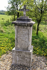 Fototapeta na wymiar Old crucifix stone pedestal with engraved text of founder
