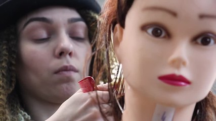 stylist practices new skills on mannequin head, move camera focus from mannequin face to hairdresser, training at hairdressing workshop, learning profession or refresher course