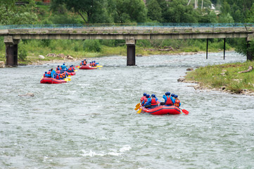 A group of men and women rafting on the river. Extreme water sport.