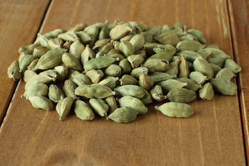 Pile of dry scattered unrefined cardamom seeds lying on wooden boards