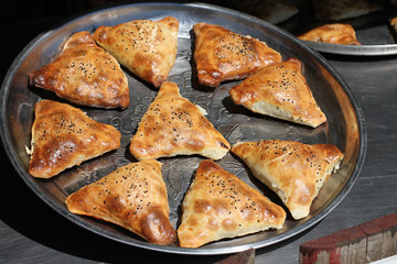 Traditional Uzbek patties (samsa) with chicken meat, lying on a large metal dish