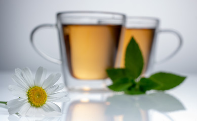 cup of herbal tea with chamomile flowers on a white table