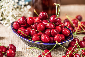 Sweet cherries with water drops in a dark plate