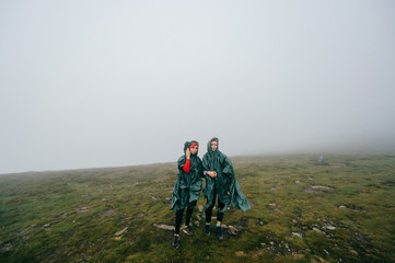 Fototapeta na wymiar Happy female couple hikers posing in foggy mountains.