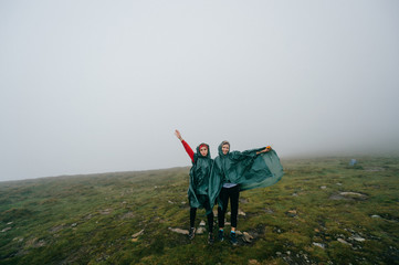 Happy female couple hikers posing in foggy mountains.