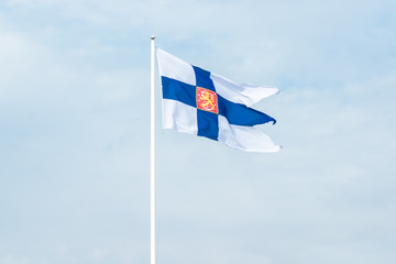 State flag of Finland with national coat of arms against blue sky