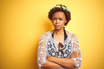 Young african american woman with afro hair wearing flowers crown over yellow isolated background...