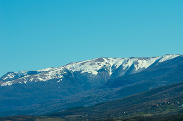 Last snow in the mountains in early spring against a clean blue sky.