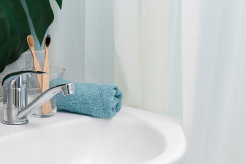 Zero waste bathroom.  Eco natural bamboo toothbrushes, blue towel and succulent on the on the sink. Green palm leaf on the background. Copy space
