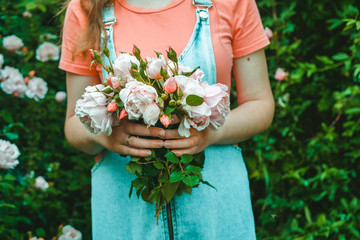 A young woman florist is holding a bouquet of pink roses. In the garden
