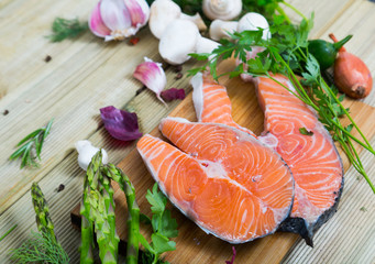 Salmon  steaks with fresh vegetables and mushrooms on wooden background