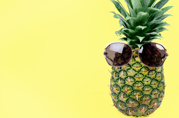 Pineapple with sunglasses on yellow background