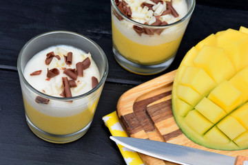 Mousse of mango with chocolate in a glasses jar on table