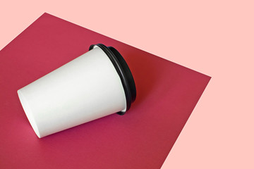 Mockup of a coffee paper cup on pink background.