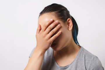 Fototapeta premium Studio portrait of a young woman. She puts her hand to her face in shame and frustration. The concept of failure and facepalm