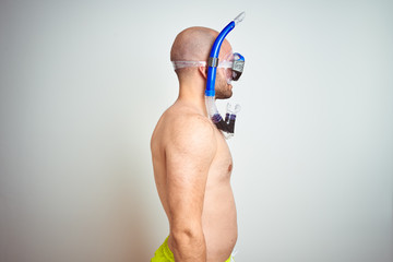 Young man wearing diving snorkel goggles equipent over isolated background looking to side, relax...