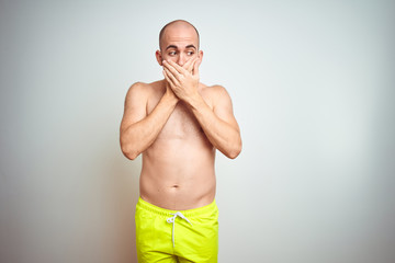 Fototapeta premium Young shirtless man on vacation wearing yellow swimwear over isolated background shocked covering mouth with hands for mistake. Secret concept.