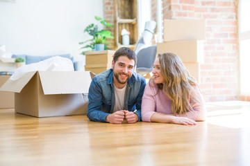 Young beautiful couple in love relaxing lying on the floor together with cardboard boxes around for...