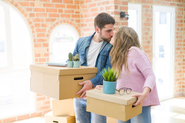 Young beautiful couple very happy together holding cardboard boxes moving to a new home