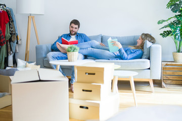 Young couple relaxing on the sofa reading a book, taking a break for moving to new house