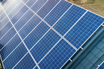 Close-up surface of blue shiny solar photo voltaic panels system on building roof. Renewable ecological green energy production concept.