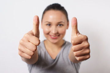 Cheerful young lady showing two thumbs up and looking at camera. Pretty woman recommending something. Recommendation concept, front view on white background