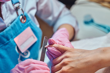 One womas is reciving nail care from another woman, wich is manicurist.