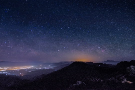 Mountain view morning at night of top hills and city around with soft fog under the stars in dark sky background, Monzone View Point Doi Ang Khang, Chiang Mai, northern of Thailand.