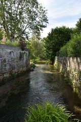 Fototapeta na wymiar La rivière passant entre les vieux murs en pierres à Mareuil ,au Périgord Vert