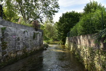 Fototapeta na wymiar La rivière passant entre les vieux murs en pierres à Mareuil ,au Périgord Vert