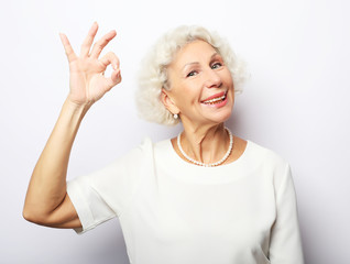 Lifestyle, emotion and people concept: Elderly happy woman giving a thumb up and looking at the camera