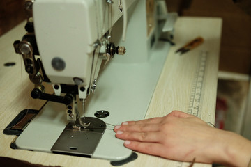 Closeup on young woman sewing leather handbag
