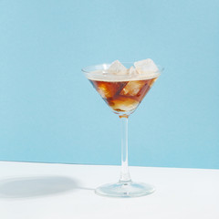 Fruit berry drink in a glass with ice on a colored background.