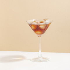 Fruit berry drink in a glass with ice on a colored background.