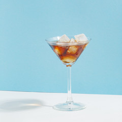Fruit berry drink in a glass with ice on a colored background.