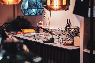Fototapeta na wymiar Master's workspace, table and beautiful colourful glass lamps at cozy workshop.