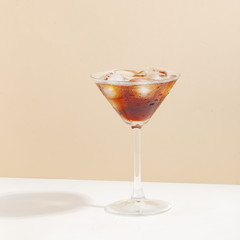 Fruit berry drink in a glass with ice on a colored background.
