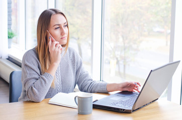 The girl sits working at the computer.