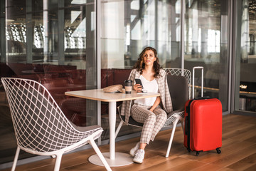 Beautiful business woman with smartphone waiting for her flight in an airport.