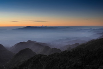 Naklejka na ściany i meble Mountain view misty morning of top hills around with sea of fog with red and yellow sun light in the sky background, sunrise at Doi Ang Khang, Monzone view point, Chiang Mai, Thailand.